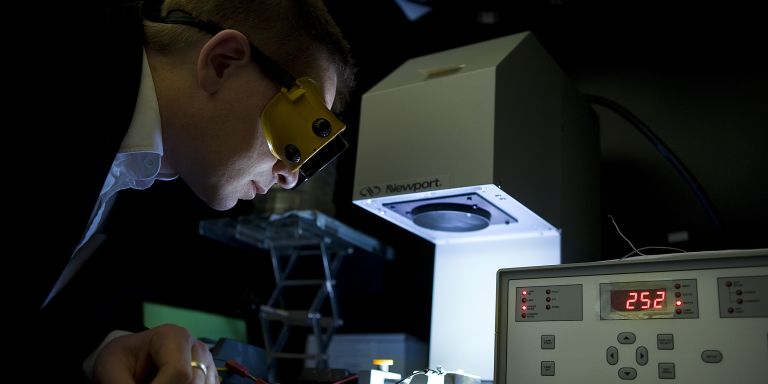 Persone med skyddsglasögen tittar på en laboration